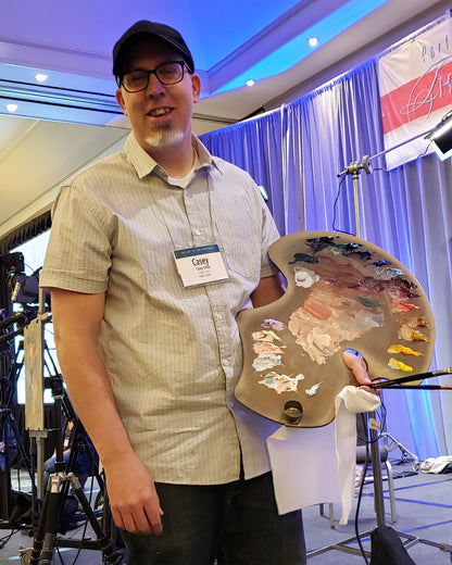 Casey Childs holding his palette of our colors at the 2024 Art of the Portrait conference!